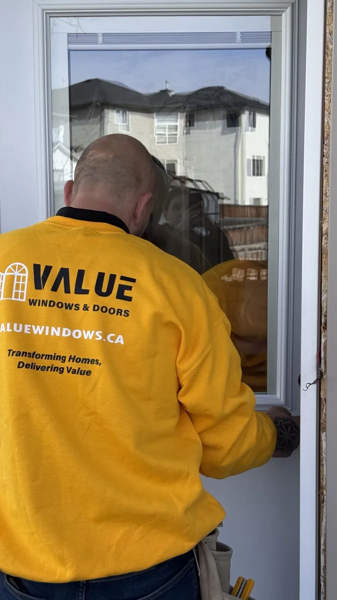 Value Windows installer examining a window frame during an Edmonton home consultation