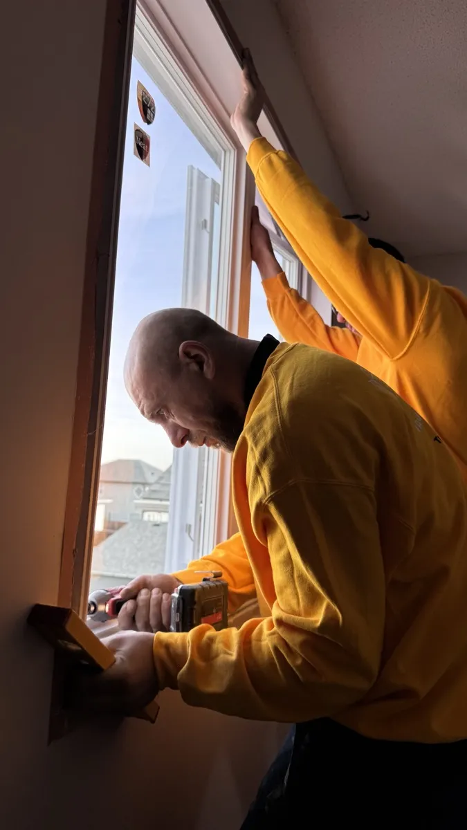 Close-up of a Value Windows installer securing a new window frame from inside an Alberta home